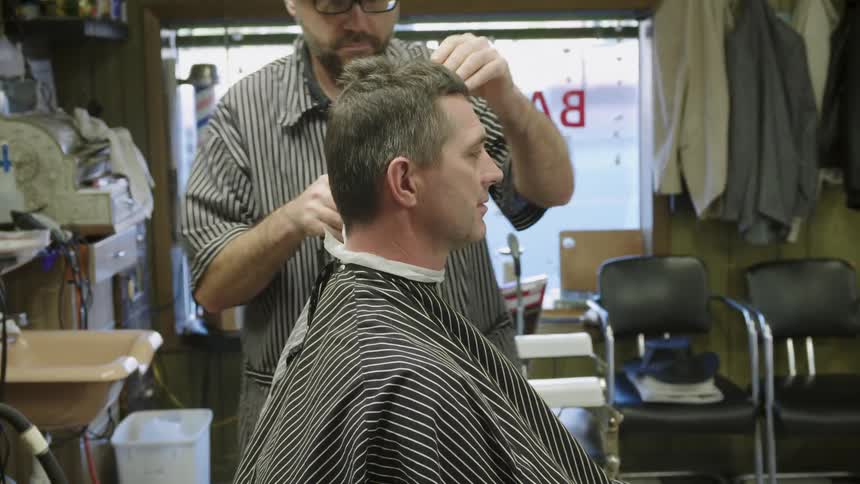 A man in a barbershop gets a haircut