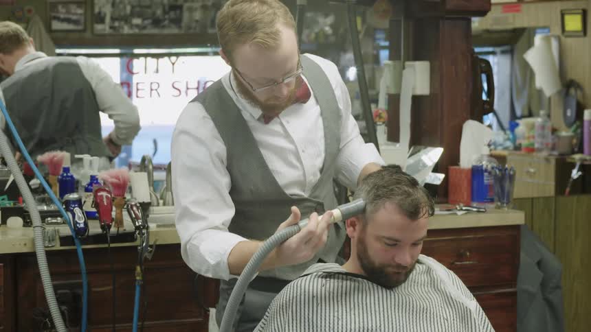 A barber works on a man's hair