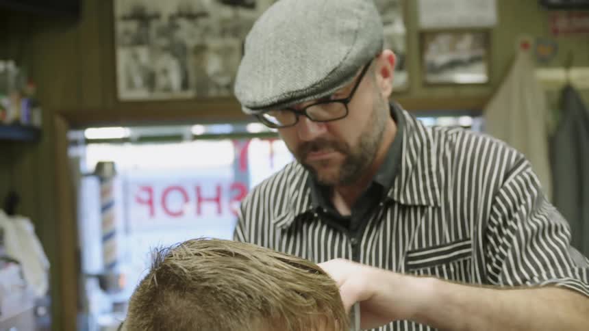 A barber uses a razor to trim a man's hair