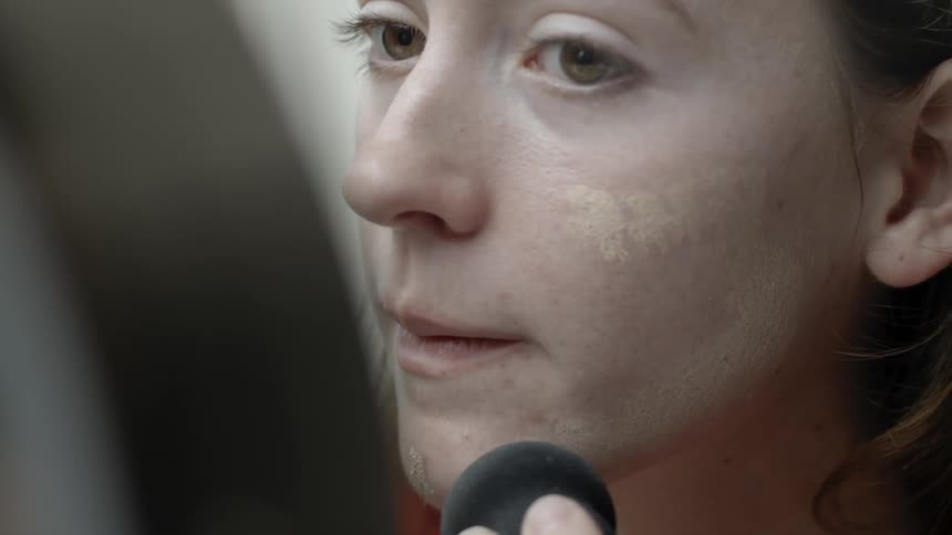 A woman blends her foundation with a black sponge