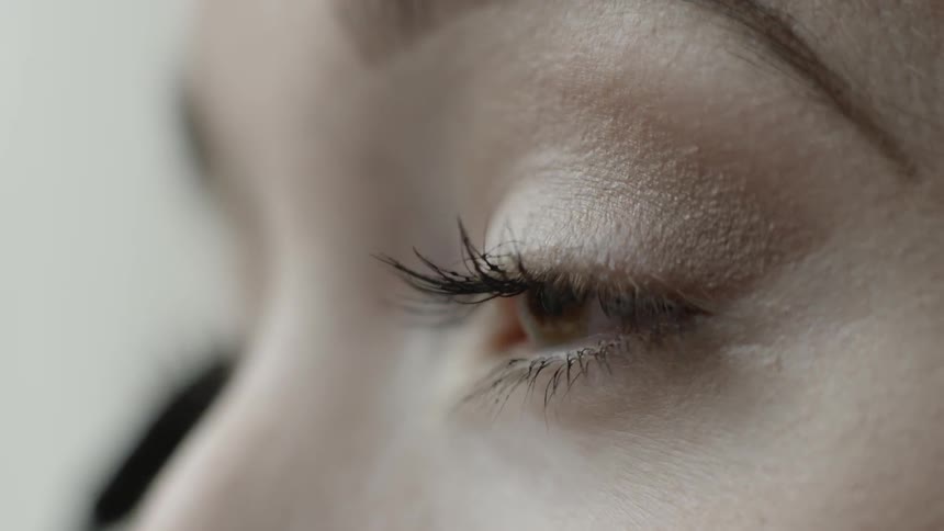 A woman applies mascara to her eyelashes
