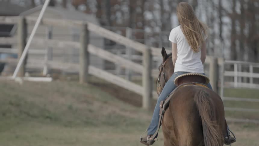 A woman is riding a horse at a slow trot