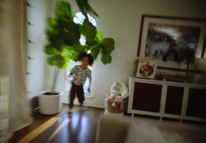 Siblings running around the living room playing