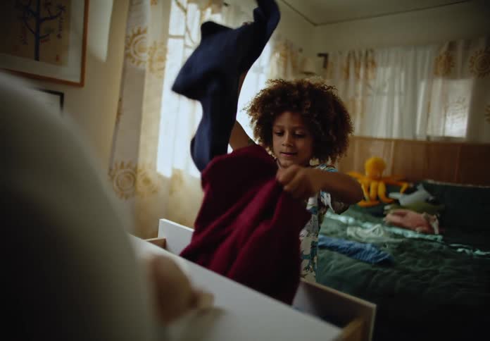 Boy taking clothes out of the closet and throwing them back in the room