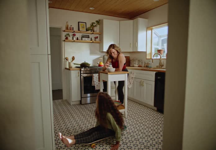 A woman and a child talking in the kitchen while eating
