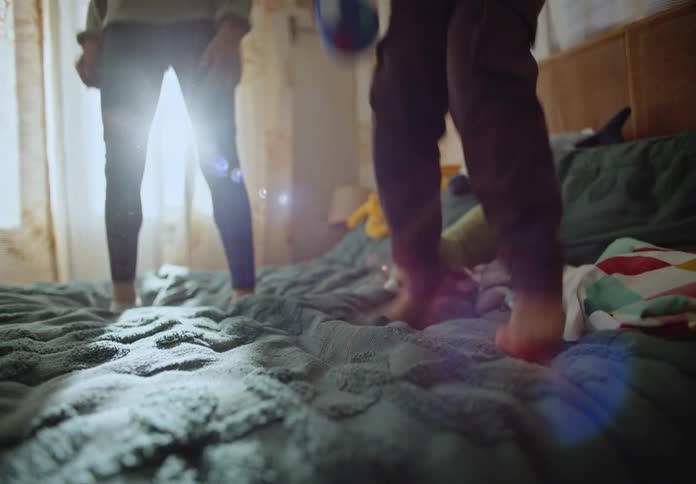 Boy and girl girl on the bed jumping happily