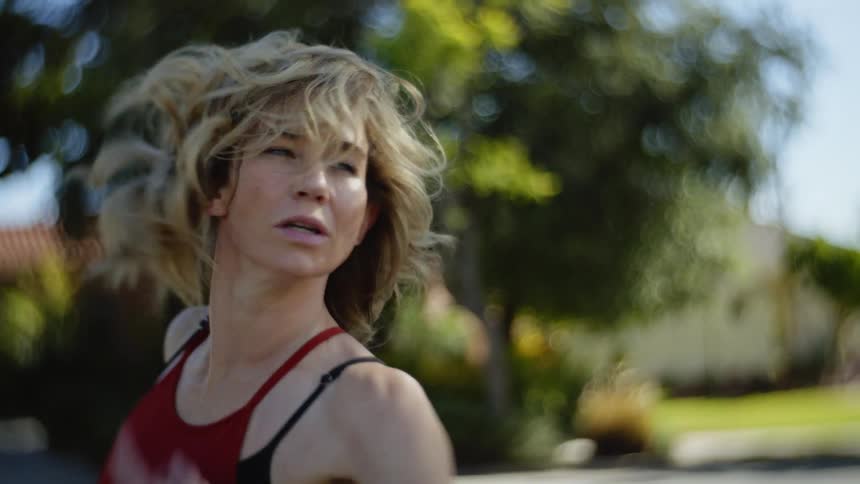 Portrait of a blonde woman dancing in the middle of a neighborhood street