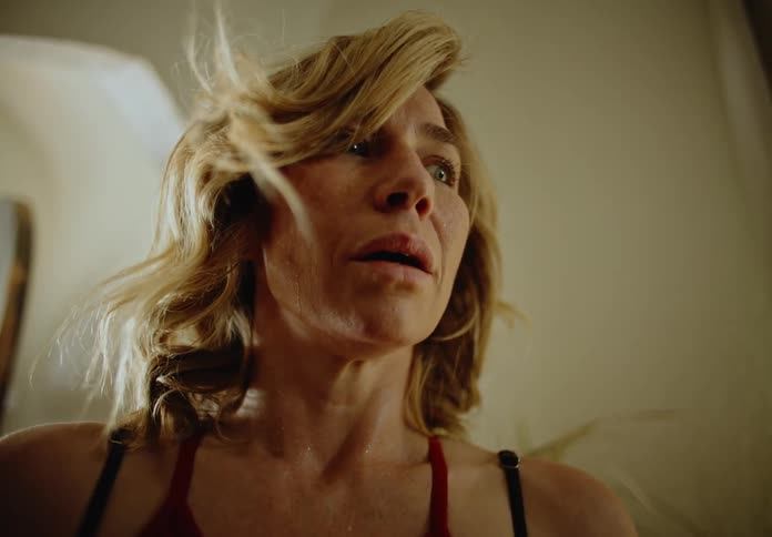 A woman staggers through a doorway and looks around fearfully