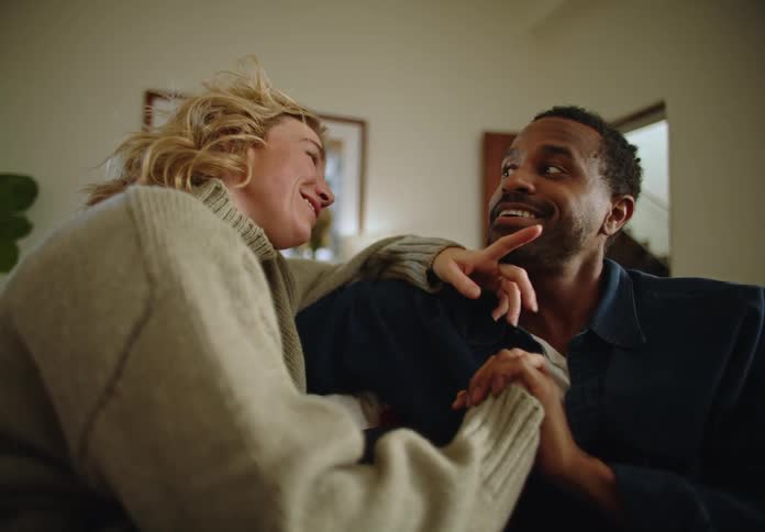 Couple sitting on couch in home hold hands while talking