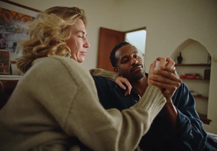 A couple sitting on a couch in the living room holding hands