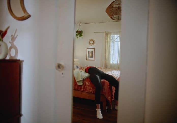 A woman sitting down and then laying down on a bed