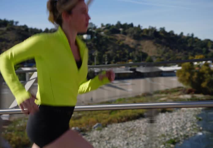 A woman running on a bridge wearing a jacket