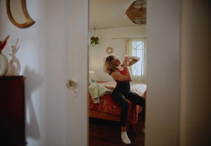 Woman in fitness clothes sitting on bed and analyzing her hands