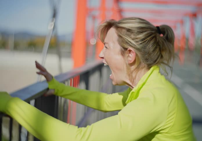 A woman screaming on a deserted bridge during the day