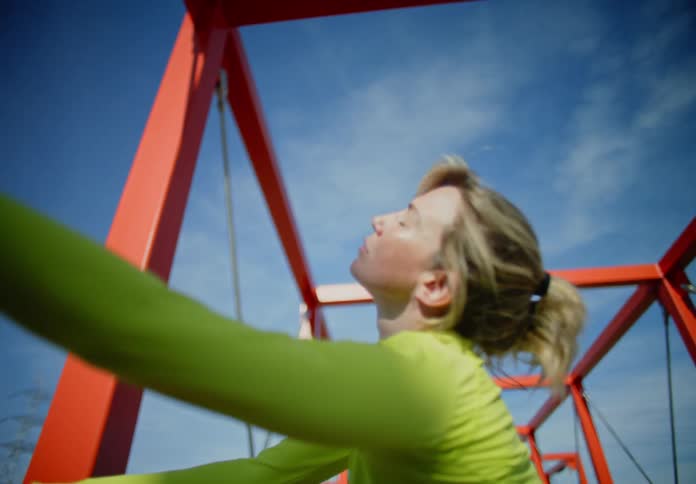 Blonde woman in fitness clothing resting her leg on the corner of a bridge and stretching her body