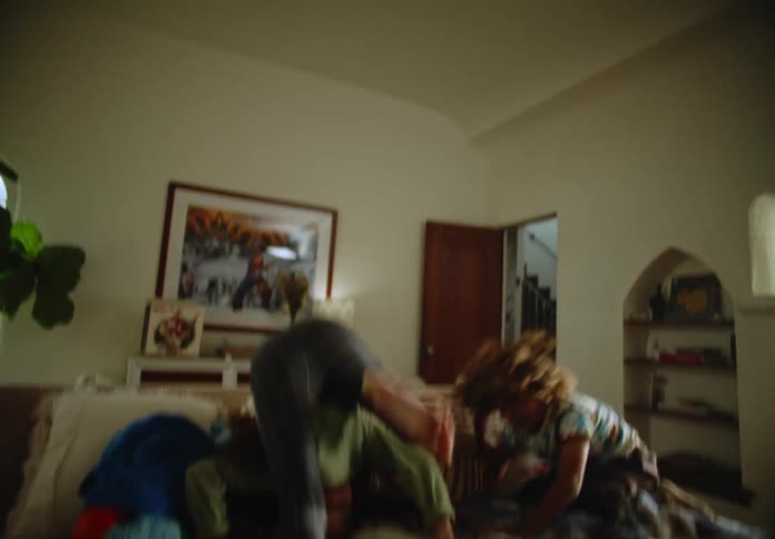 Two children rolling around and playing on a living room couch