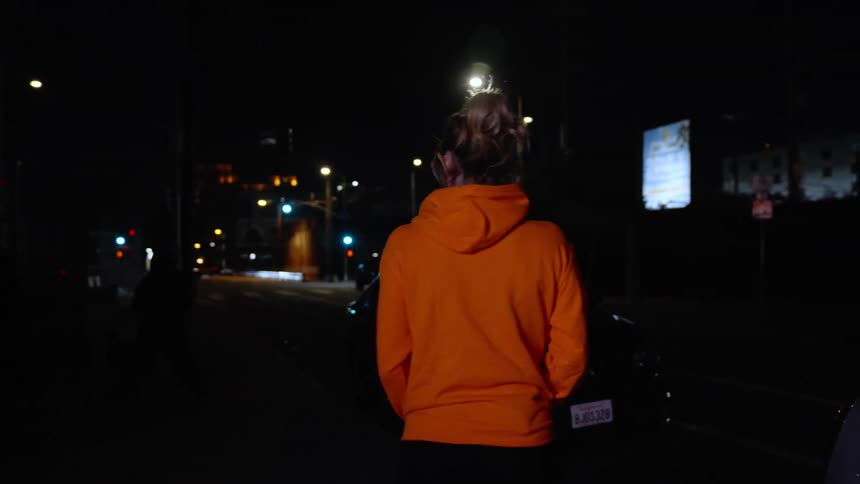 A woman walking around a city at night