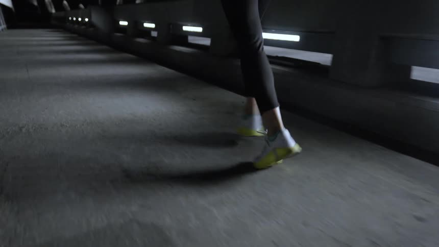 A woman jogs on a path on a bridge