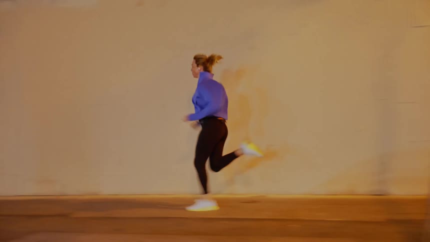 A person in a blue top and dark pants running on the sidewalk