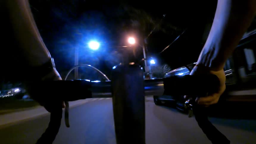 View from the handlebars of a bicycle riding through the city at night