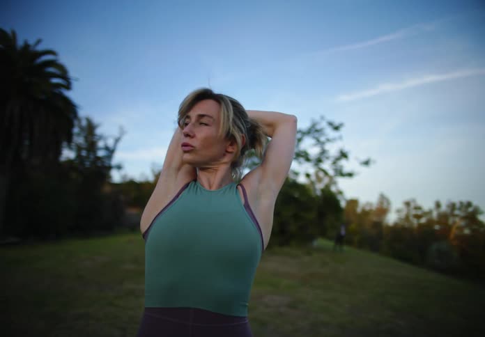 Fit woman stretches on a park before workout at morning