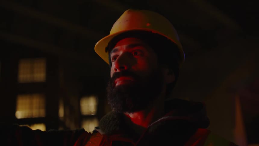 Portrait of a working man wearing his safety helmet at night and making a hand signal