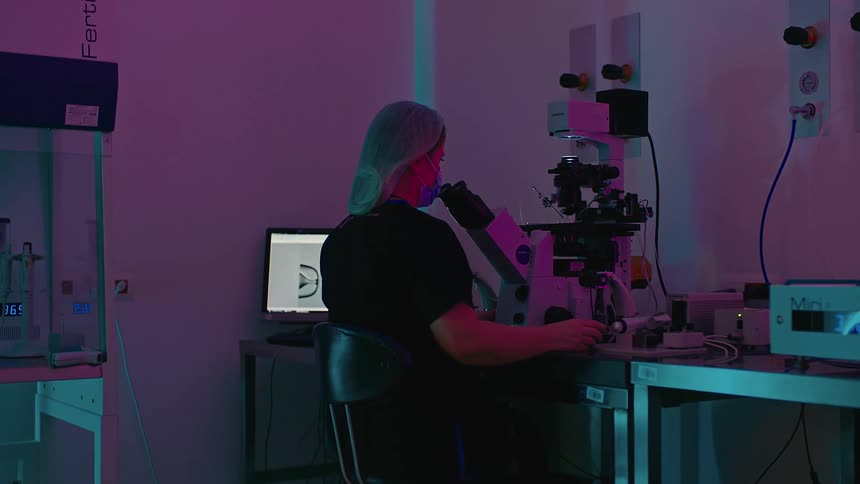 A woman looking into a lab microscope