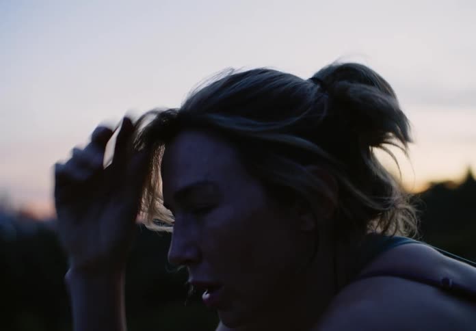 Lady stops to relax during a jog at sunset