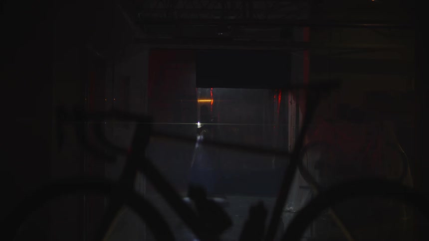 Man walks into dark room using phone for light and heads toward bicycle