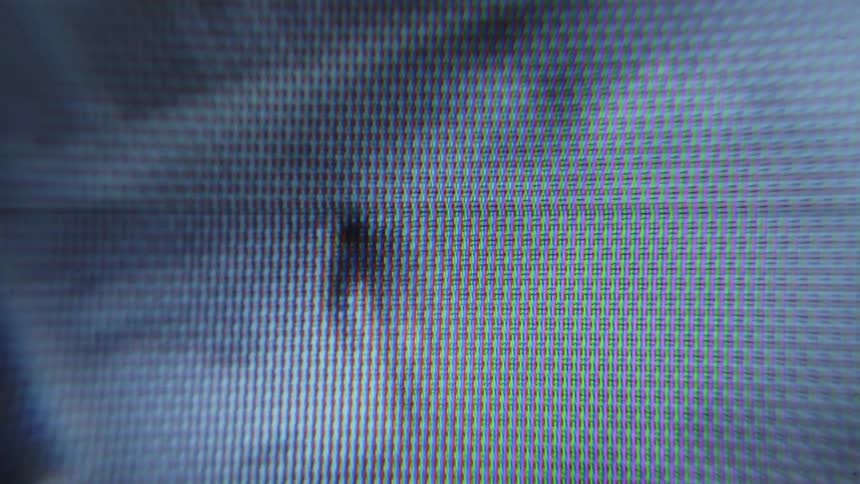 Closeup view of a screen displaying pixelated and distorted footage of a person riding a bicycle on an alley