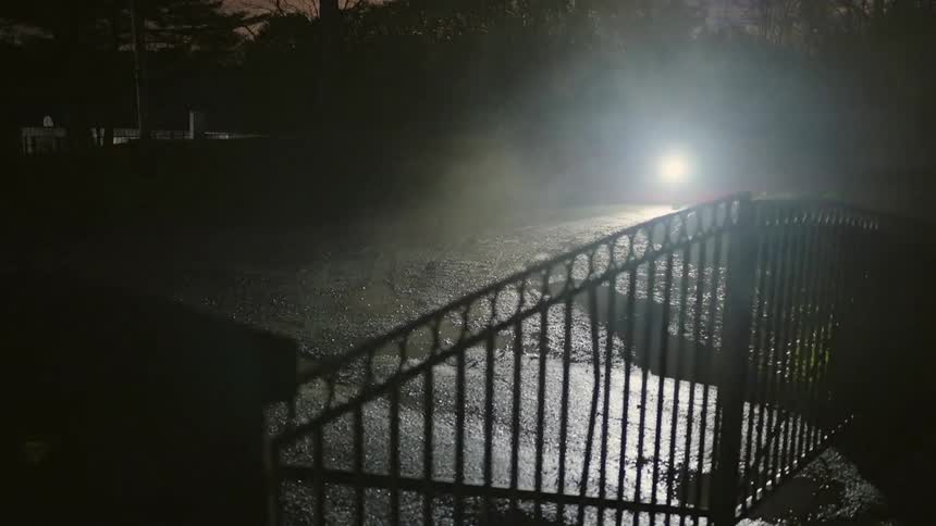 A person riding a bicycle through the fog in the streets at night