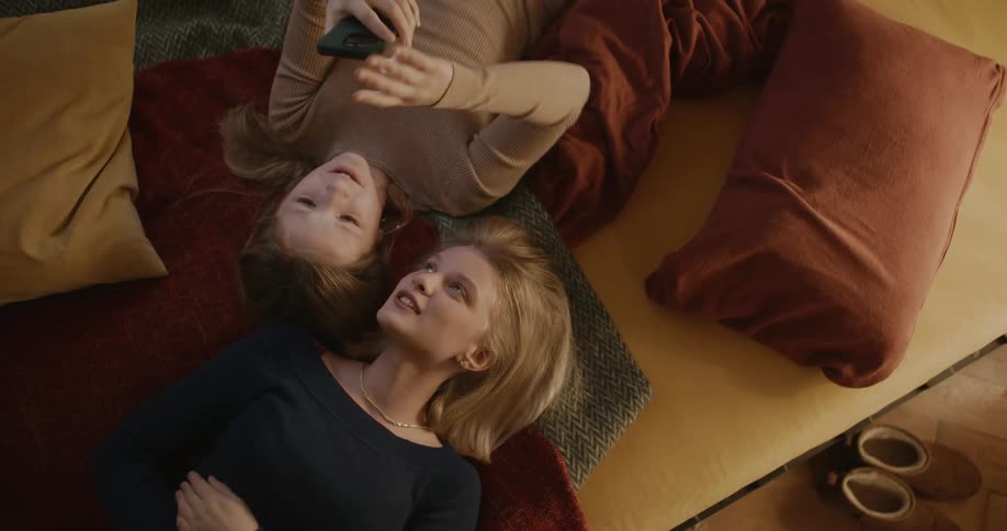 Portrait of a teenager and a child lying on the sofa using their cell phones