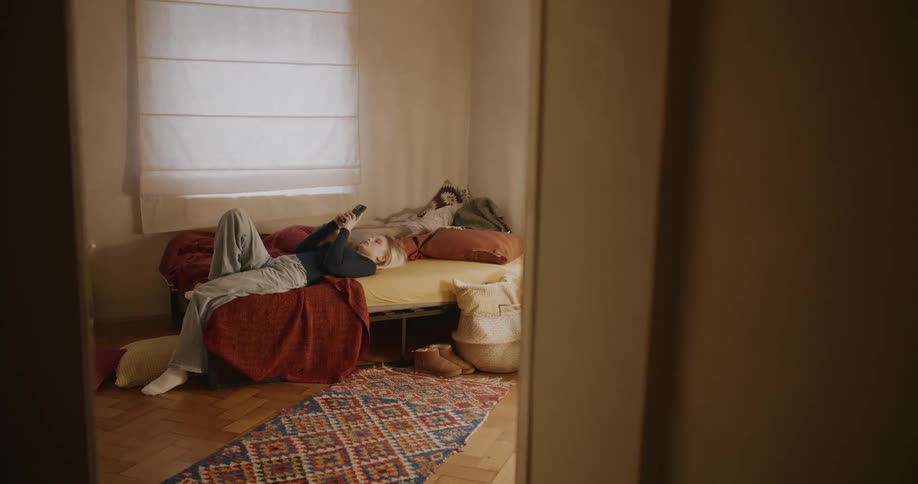 Two teenage girls on a bed looking at their smart phones
