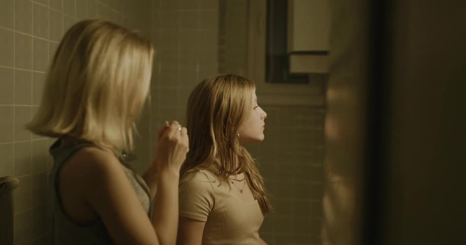 Young woman applying eye makeup to a teenager in the bathroom