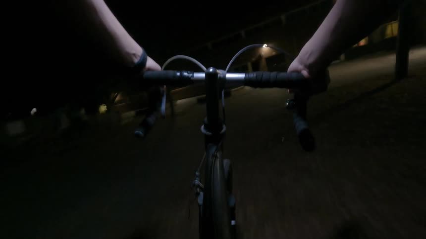 Male cyclist pedals through urban streets at night