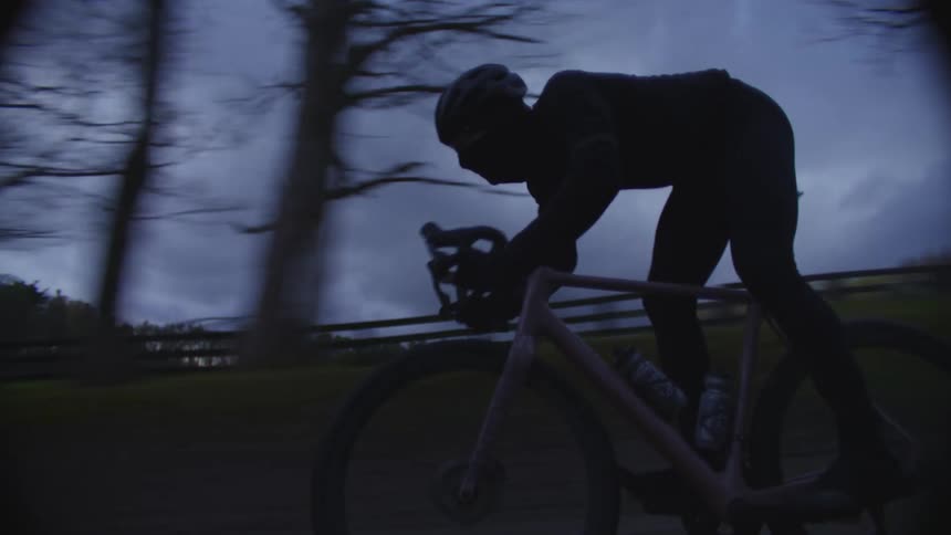 A person is cycling outdoors during the evening