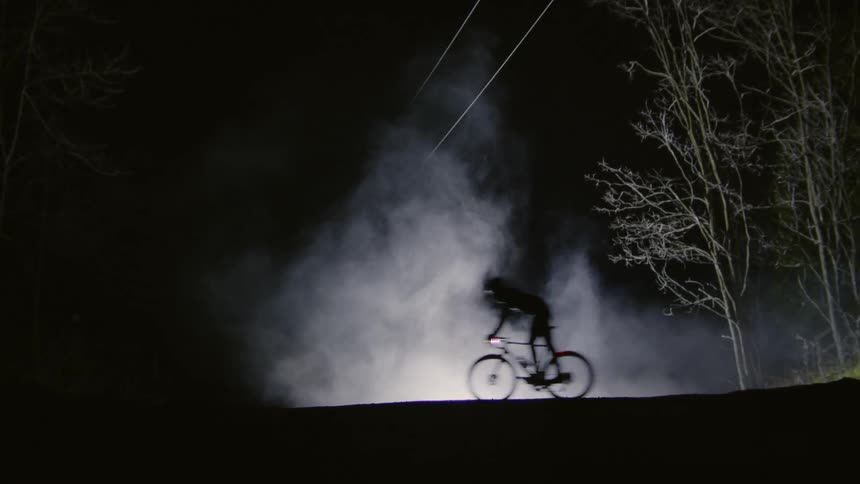 Man riding a bicycle at night on a hill