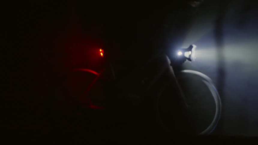 A person on a bicycle going through a dark foggy forest at night