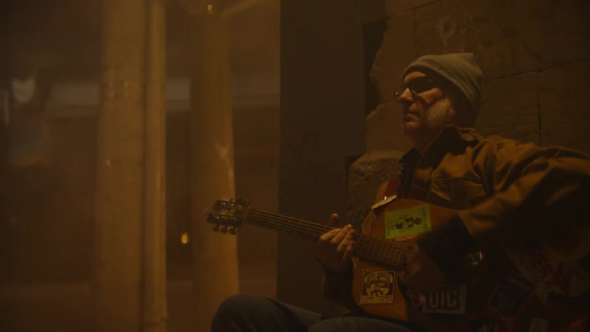 A clip of a man playing guitar on the street in the night