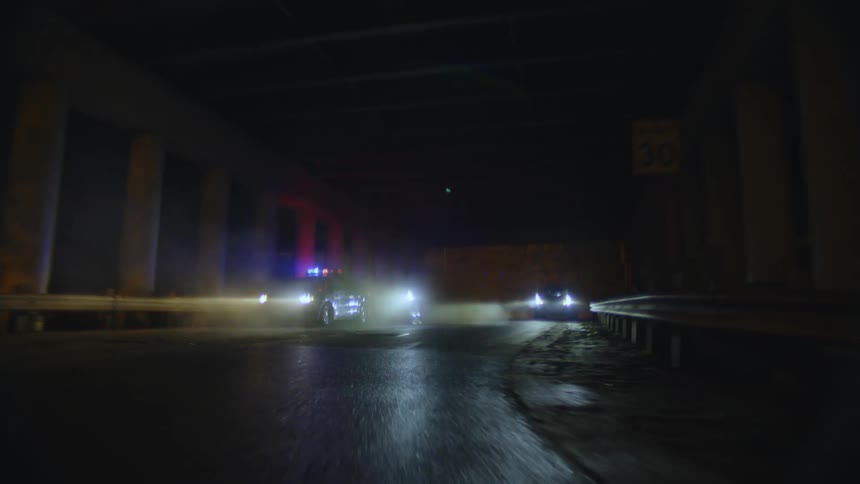 Person cycling at night at high speed and passing through an overpass with police cars