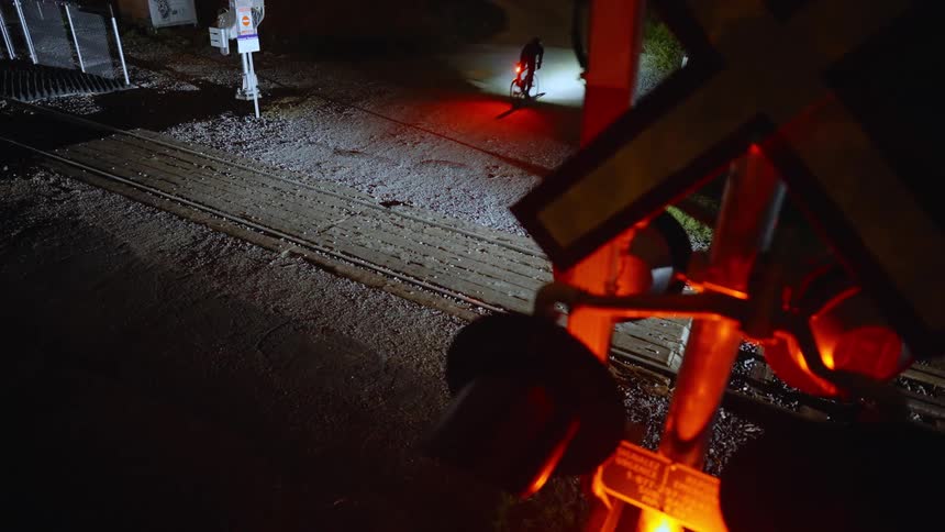 Person rides bicycle over the railline at night