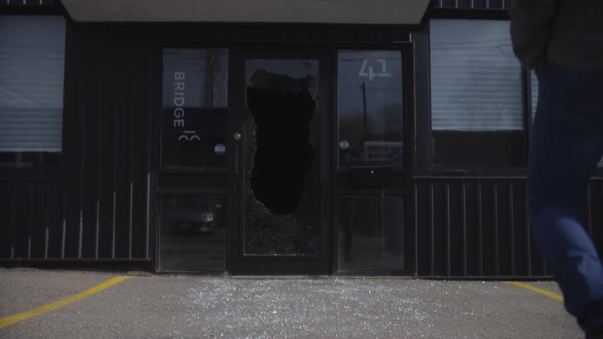A person walking on shards of glass from a broken door