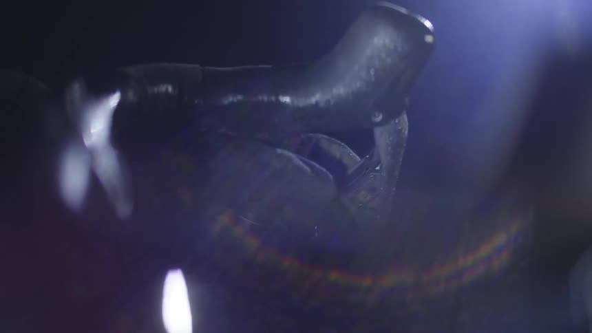 Blurry visual of a moving bicycle at night with a hand on its handle