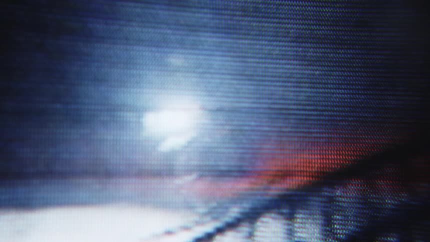Video being played on a small screen of a man passing by on a motorcycle at night