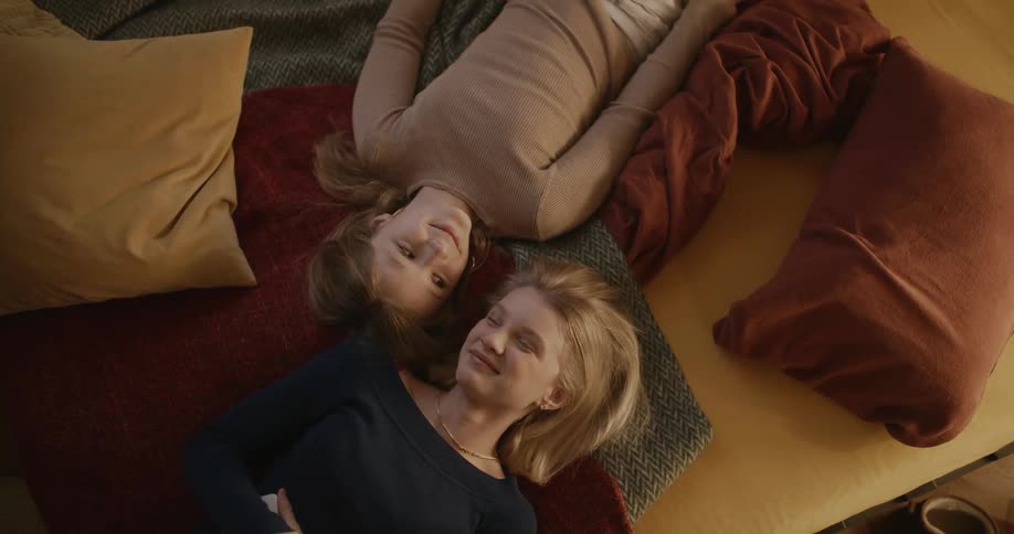 Two teenagers laugh in bed