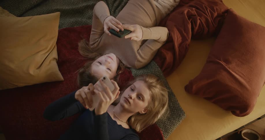 Portrait of a woman and a child lying on a bed using a cellphone