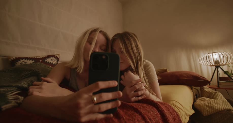Two teenagers have fun taking selfies in the bedroom