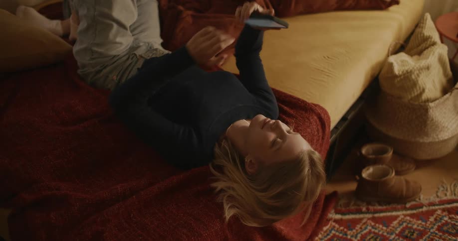 Young blonde woman lying in bed using her cell phone and me hanging up afterwards