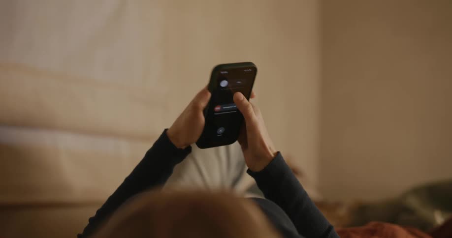 Woman lying in bed and turning off her cell phone