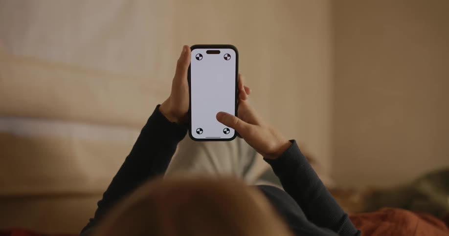 A girl is using her cell phone in bed